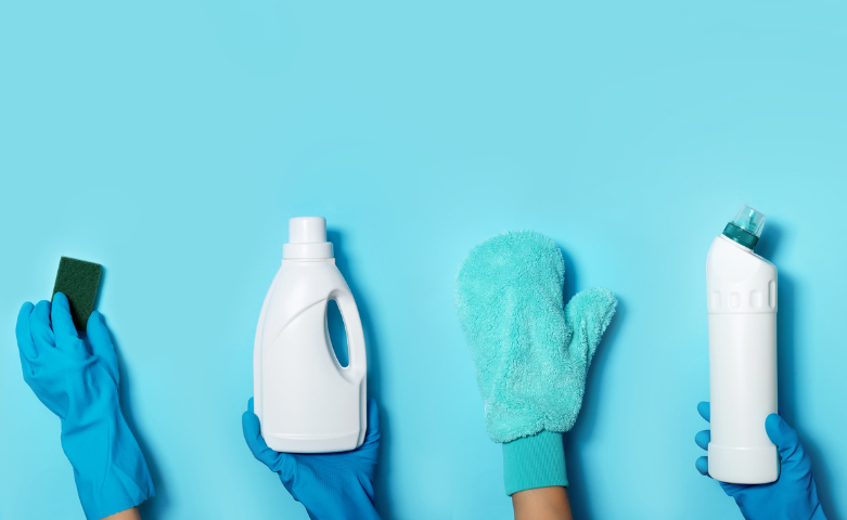 Eco-friendly and traditional cleaning products held by hands in blue rubber gloves against turquoise backdrop